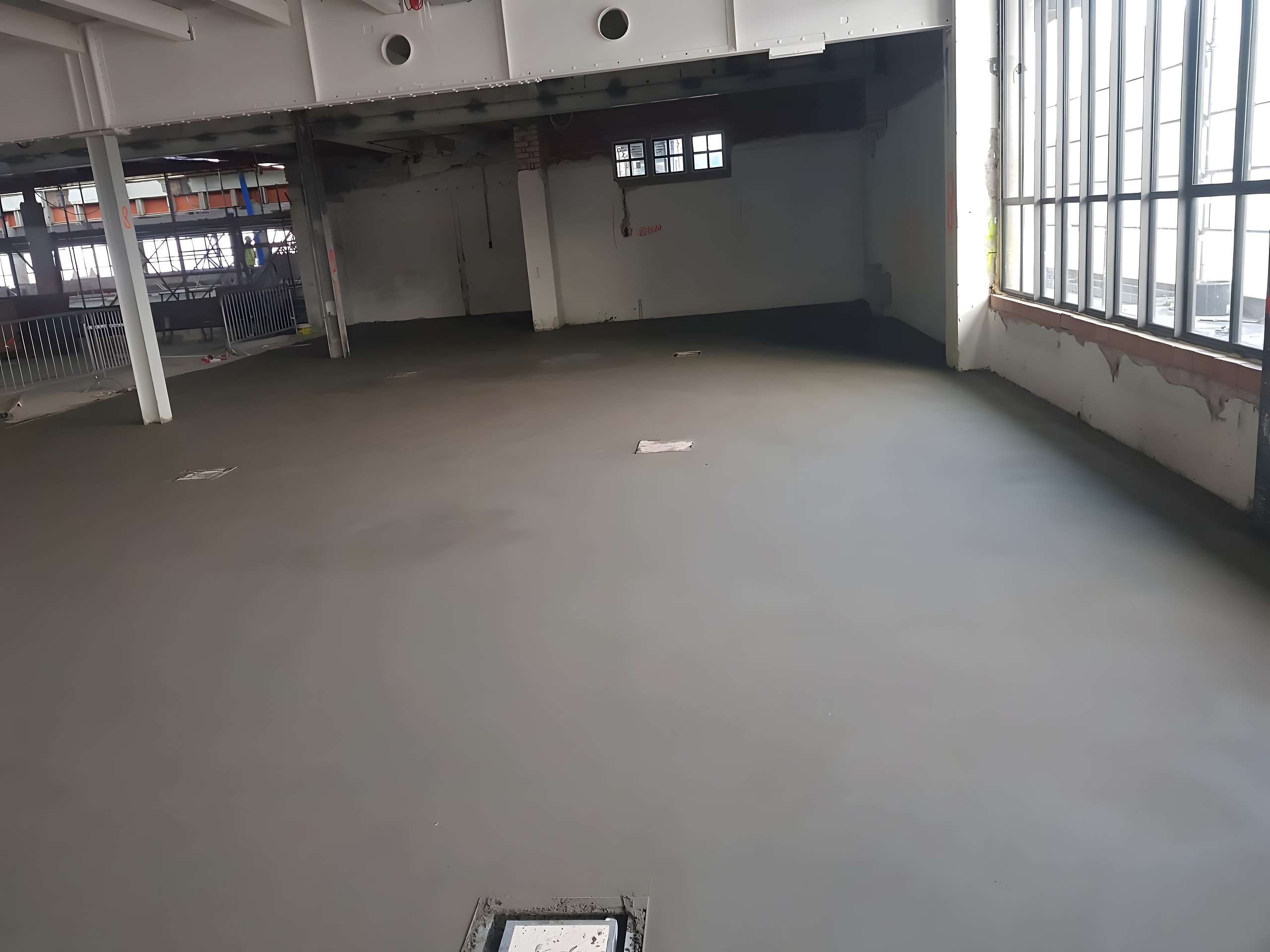 Verse zandcement dekvloer in een hal met daglicht