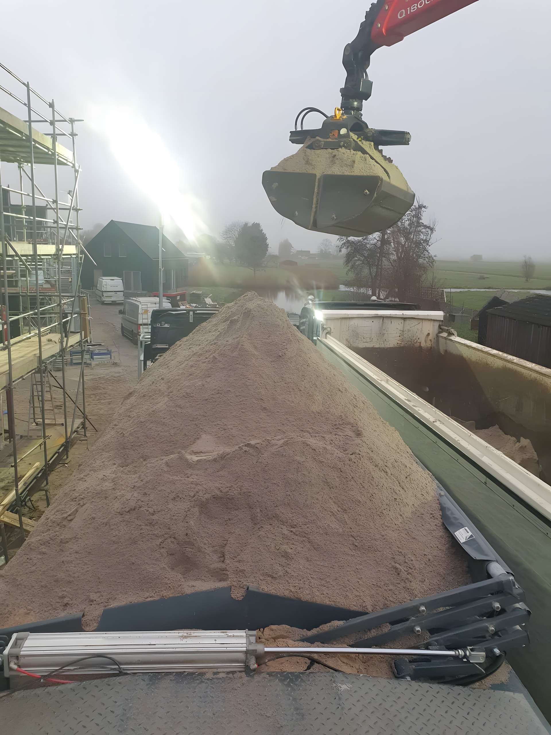 Zandlevering met kraan op de bouwplaats