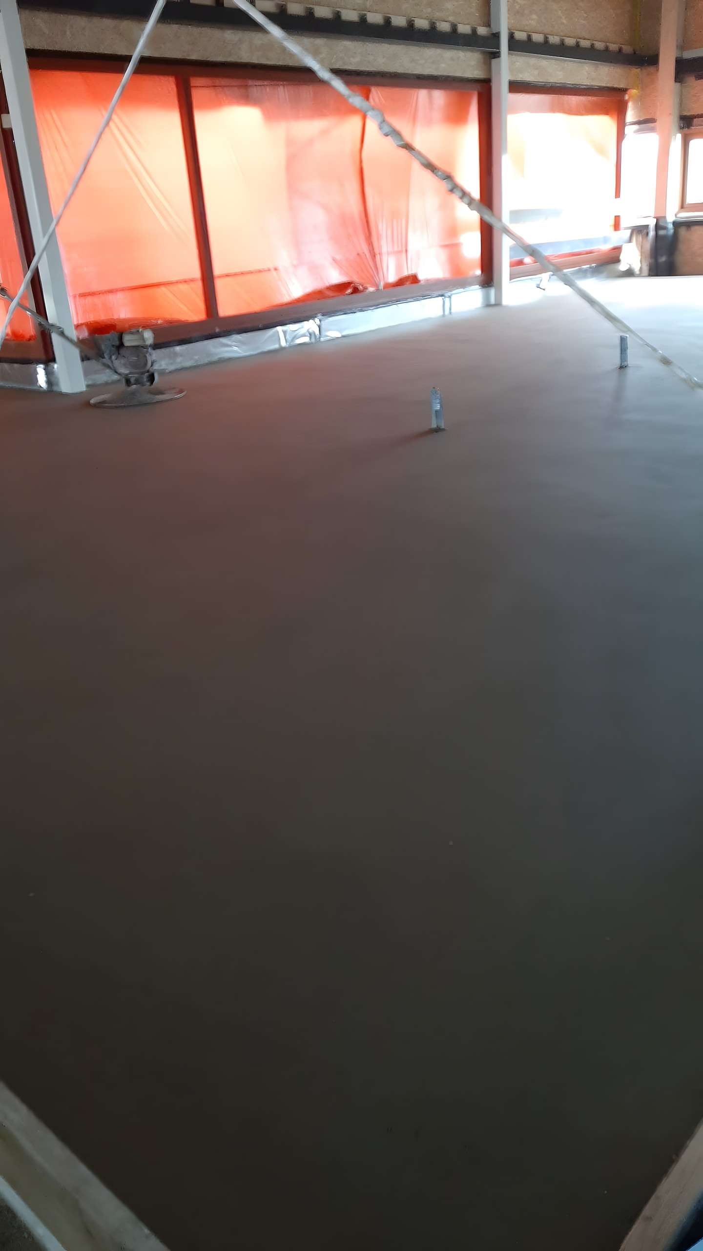 Verse dekvloer in een ruimte met rood bouwscherm