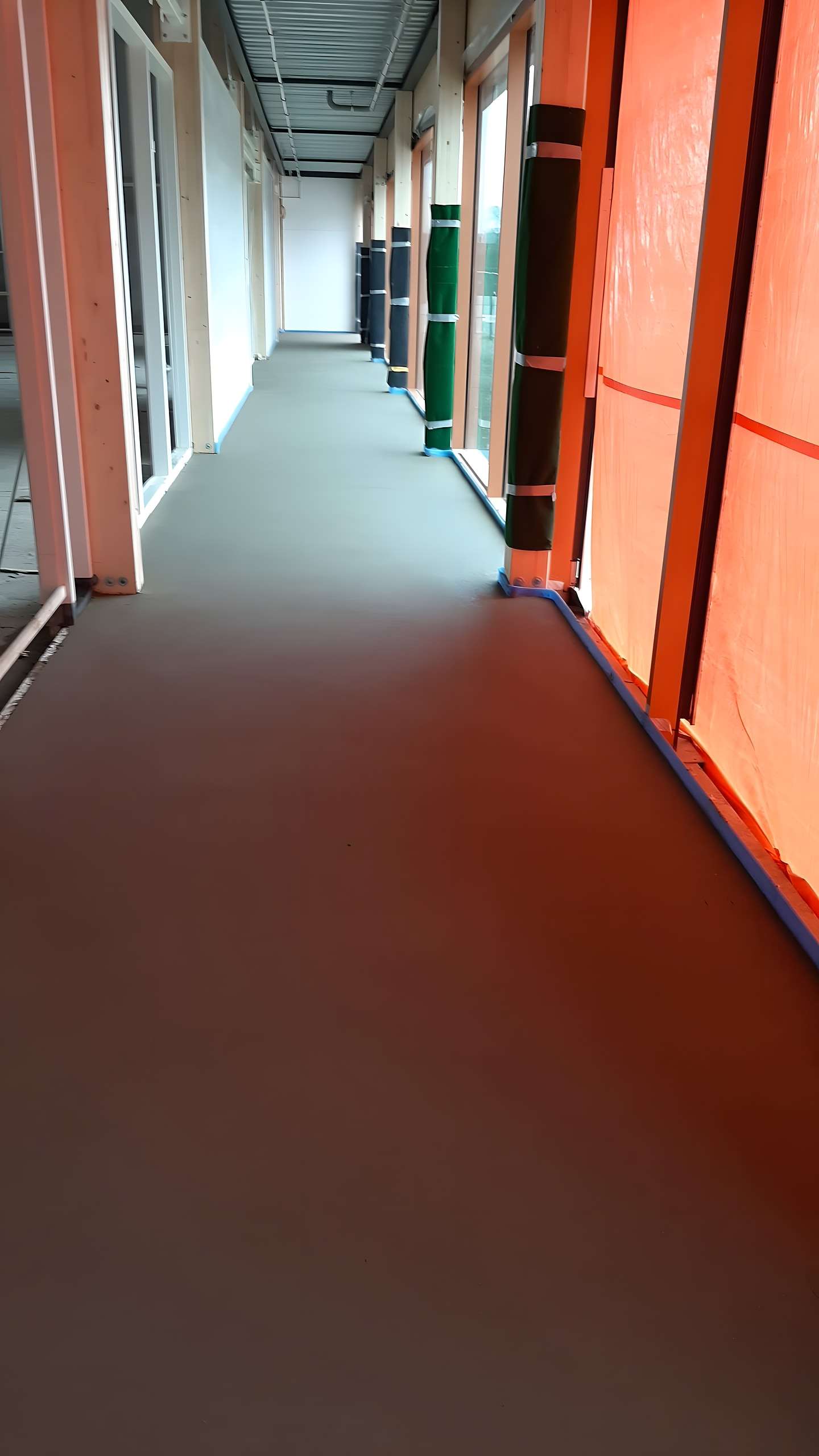 Gang met afgewerkte dekvloer en afgeschermde ramen